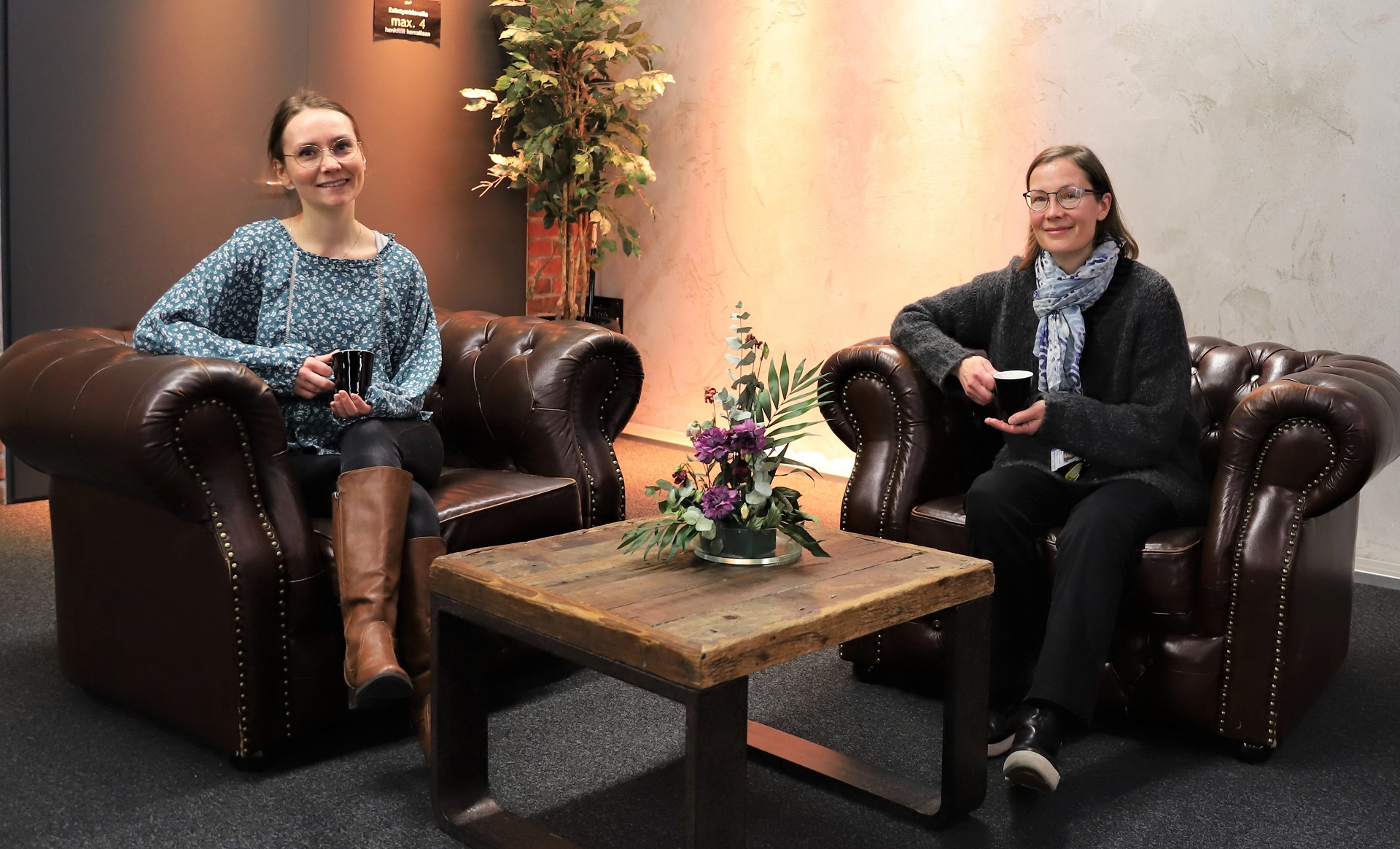 Perhetyöntekijät istuvat sohvilla ja juovat kahvia