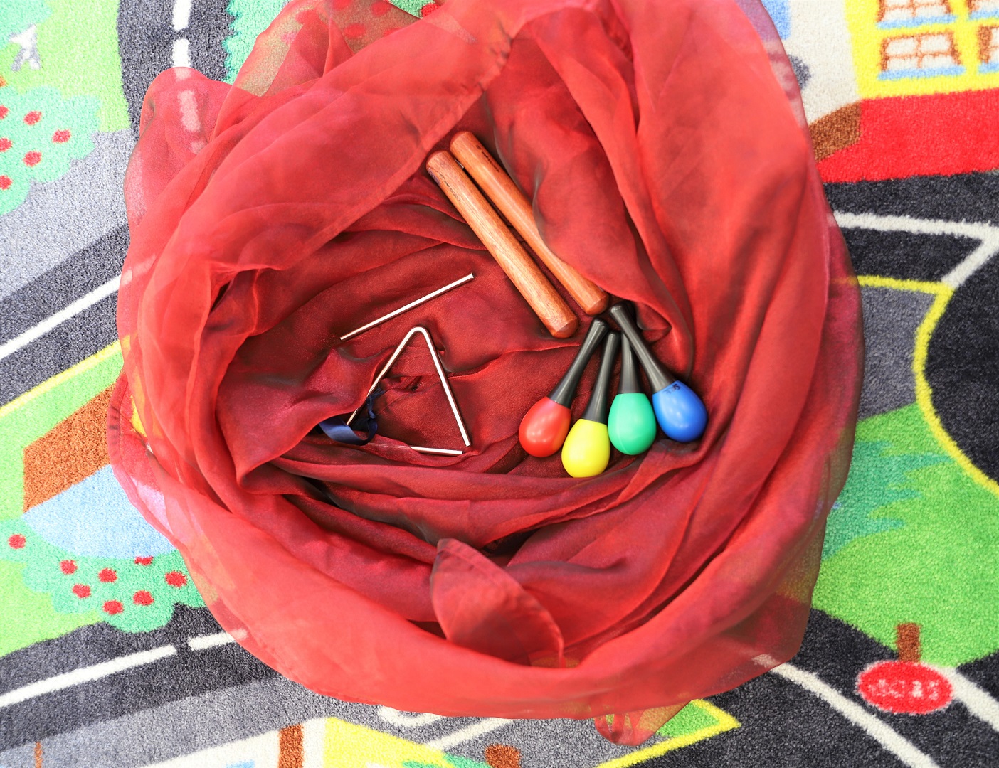 Soittimia lattialla. Marakasseja, kapuloita ja triangeli.