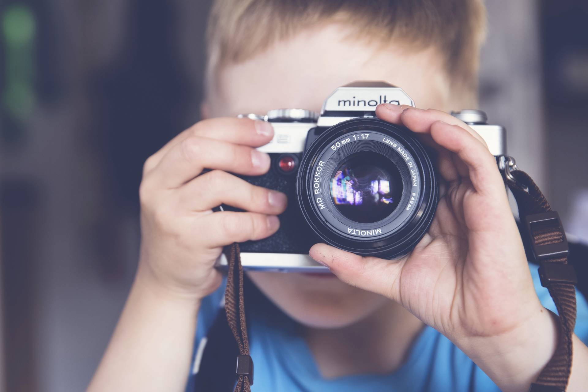 Lähikuva pojasta, joka kuvaa vanhalla järjestelmäkameralla.