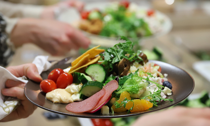 Kuvassa on tummalle lautaselle kerätty ruokia noutopydästä.